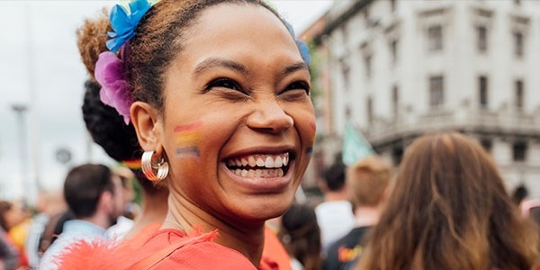 Happy woman with rainbow flag painted on face